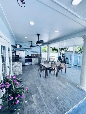 Covered patio featuring recessed lighting, ceiling fans, stone veneer kitchen island, and plank tile flooring