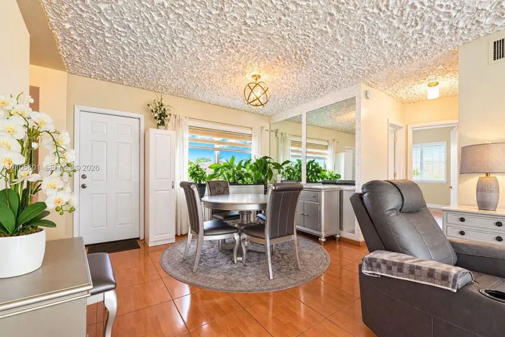 Tile flooring throughout, paneled entry door, recessed lighting fixture, mirrored wall accent, and built-in cabinetry