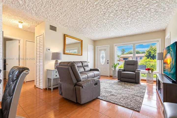 Tiled flooring throughout, featuring a prominent front door with an oval glass insert