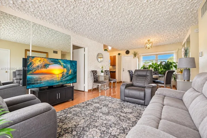 Living area featuring wood-finish flooring, mirrored wall panels, and a decorative ceiling light fixture