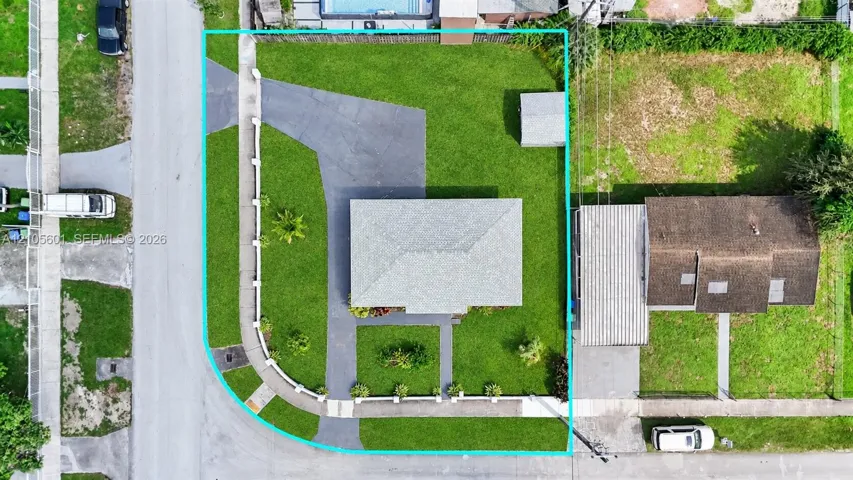 Manicured lawn with mature landscaping, paved driveway, and detached storage shed