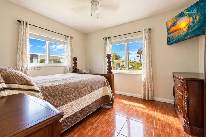 Wood-finish tile flooring, dual windows with white frames, and a ceiling fan with integrated lighting