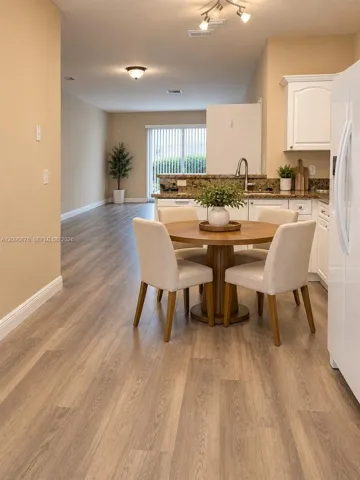 Hard-surface wood-finish flooring throughout, track lighting, ceiling-mounted light fixture, white cabinetry, and a sliding glass door