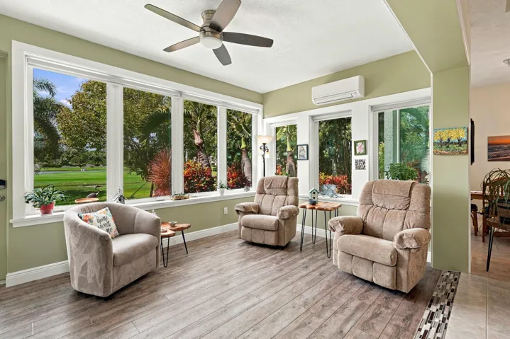 The enclosed sunroom features a wall of impact windows. Enjoy beautiful sunsets, watching golfers, and enjoying morning coffee or an evening cocktail.
