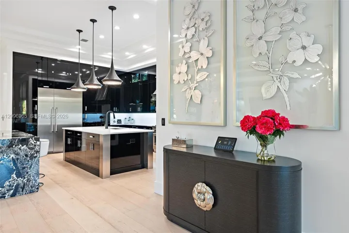 Kitchen featuring high-gloss black cabinetry, white countertops, stainless steel refrigerator, matte black faucet, and pendant lighting