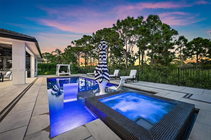 In-ground swimming pool with a Baja shelf, integrated spa, tiled pool decking, and metal perimeter fencing