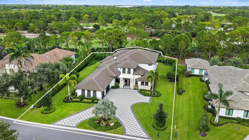Multi-level residence featuring a concrete tile roof, patterned paver driveway, manicured lawn, and mature landscaping