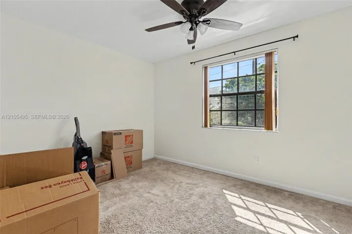 Room featuring wall-to-wall carpeting, a multi-pane window with a curtain rod, and a ceiling fan with integrated lighting