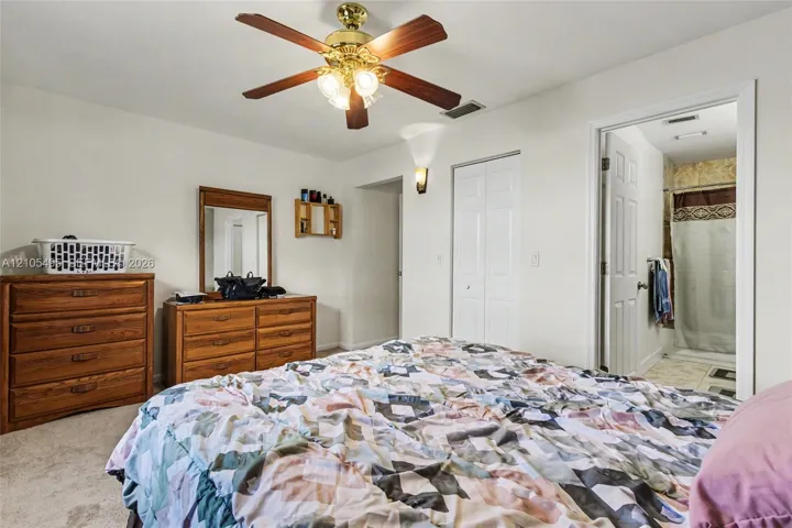Room featuring a ceiling fan with integrated lighting, wall-mounted sconce, neutral carpeting, and a dual-panel closet door