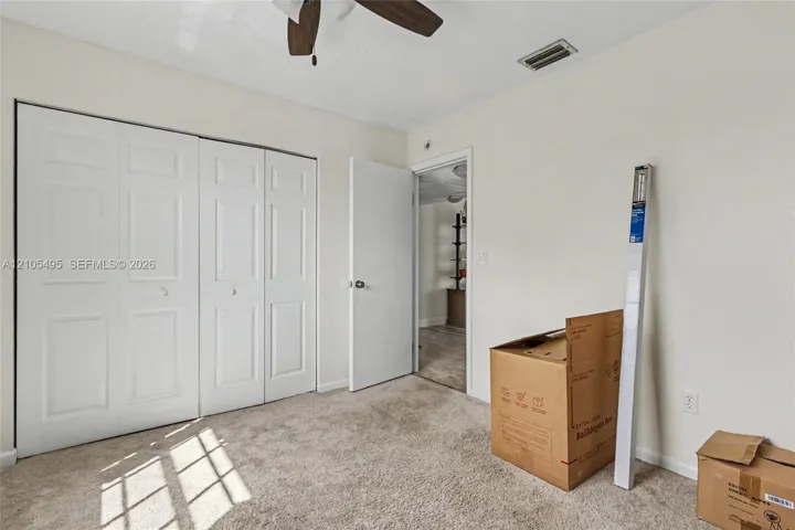 Neutral-toned interior featuring wall-to-wall carpeting, bi-fold closet doors, and a ceiling fan