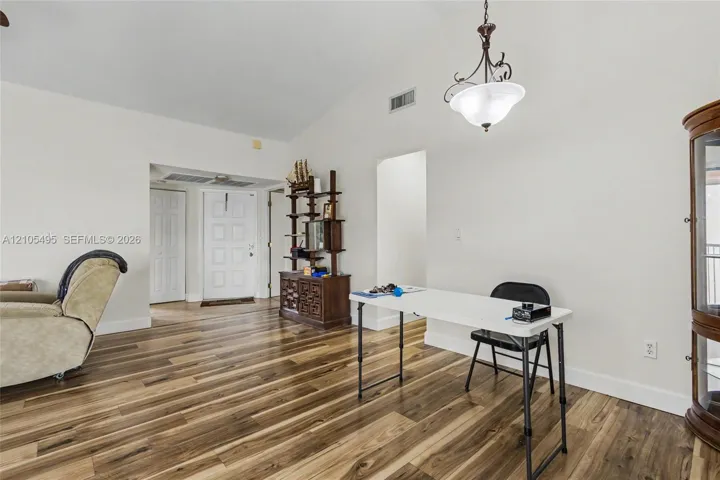 Vaulted ceilings, wood-finish flooring, and an ornamental metal and glass pendant light fixture