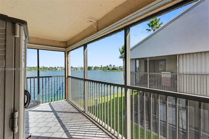 Screened-in balcony featuring tile flooring and metal railings overlooking a lake
