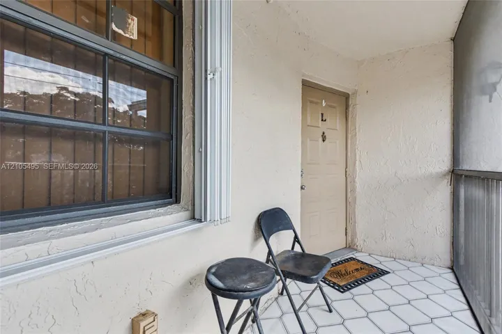Screened porch entry featuring white hexagonal tile flooring, a multi-pane grid window, and a paneled door with a metal knocker