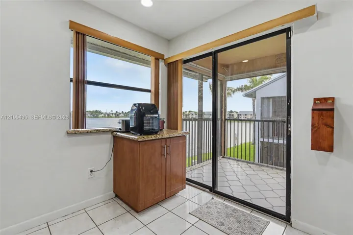 Built-in wooden cabinetry featuring stone-finish countertop, tile flooring, and glass sliding doors opening to a screened balcony with metal railing