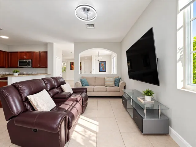 Neutral tile flooring, arched wall cutout, and circular LED ceiling fan fixture