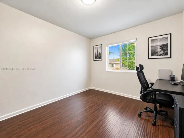 Room featuring wood-finish flooring, neutral walls, and a multi-pane sliding window