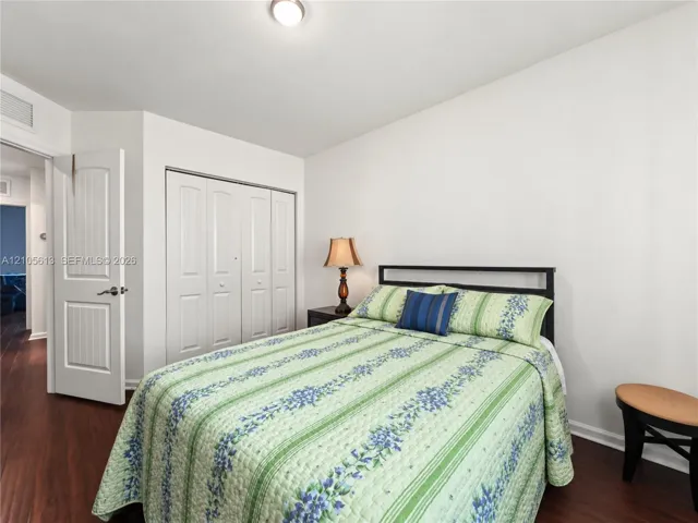 Room featuring wood-finish flooring, a multi-panel interior door, and a built-in closet with folding doors