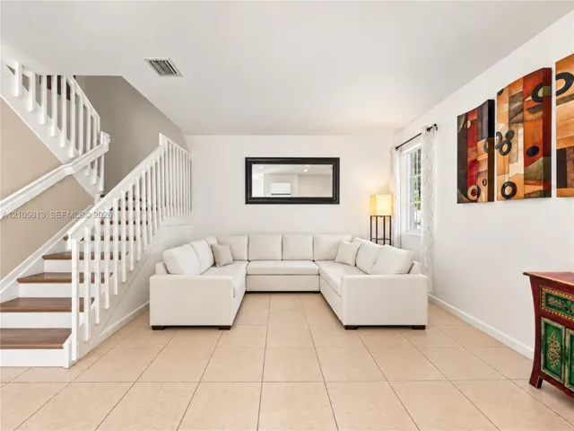 Open-concept interior featuring large-format ceramic tile flooring, a staircase with white balusters and wood-finish treads, and a window with neutral drapery