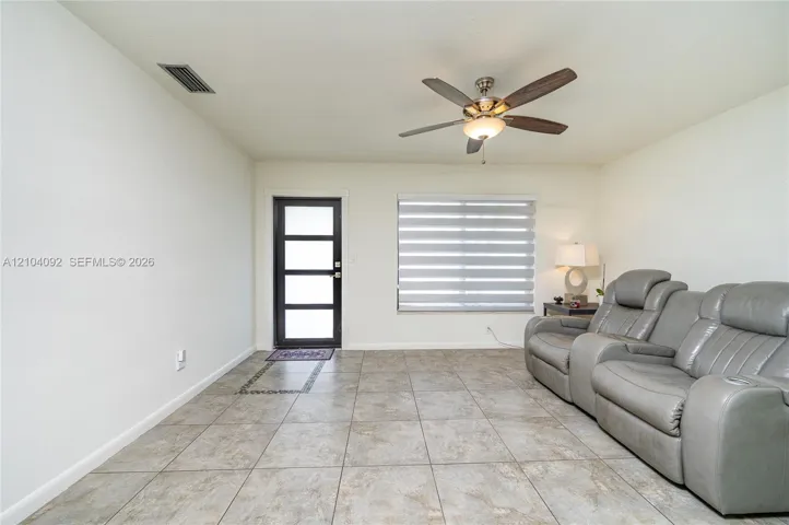 Neutral-toned tile flooring, four-panel glass-inset entry door, ceiling fan with integrated lighting, and horizontal window blinds