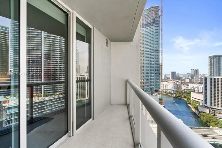 Balcony with tiled flooring, clear glass railing, and sliding glass doors