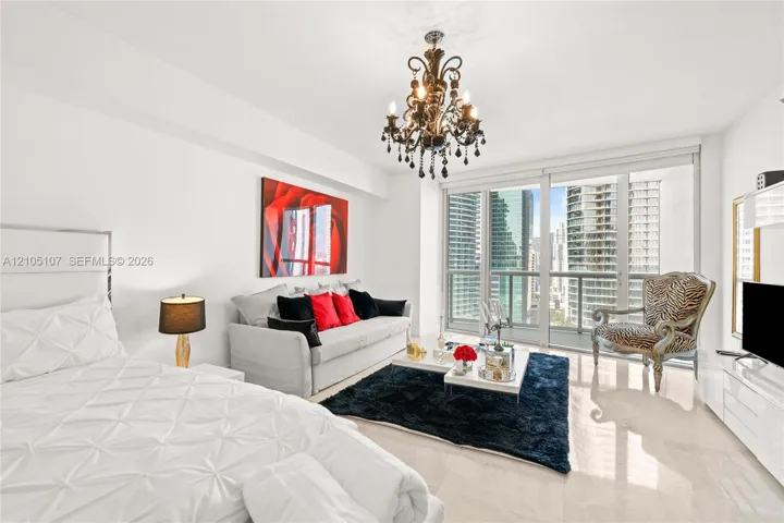 Polished tile flooring throughout, featuring a decorative chandelier and full-height glass doors