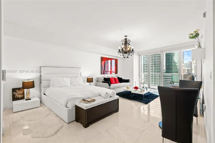 Light-toned tile flooring throughout, white walls, full-height glass doors, and a black chandelier