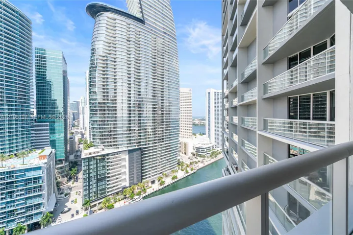 Balcony with glass railings overlooking a cityscape and a waterway