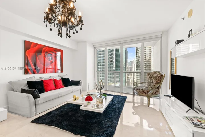 Chandelier lighting, full-height windows, balcony access, built-in shelving, and light-toned tile flooring