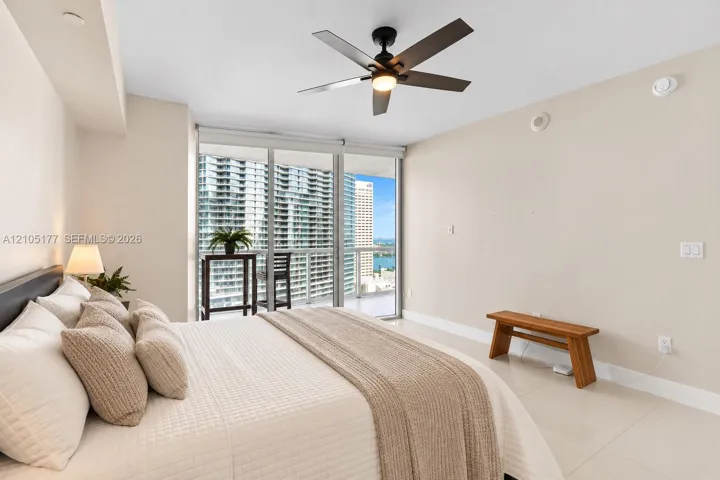 Floor-to-ceiling glass sliding doors, polished tile flooring, ceiling fan with integrated lighting, and access to a private balcony