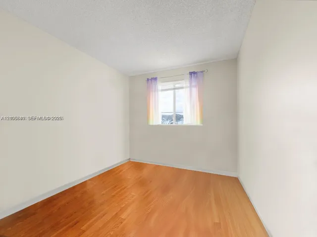 Interior room featuring wood-finish flooring, textured ceiling, and a window with natural lighting