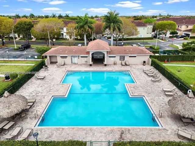 Swimming pool with paver decking, covered pavilion, tile roofing, and integrated tiki-style structures