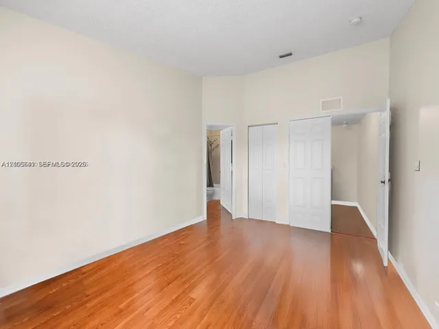 Interior space featuring vaulted ceilings, wood-finish flooring, and multiple sets of bifold closet doors