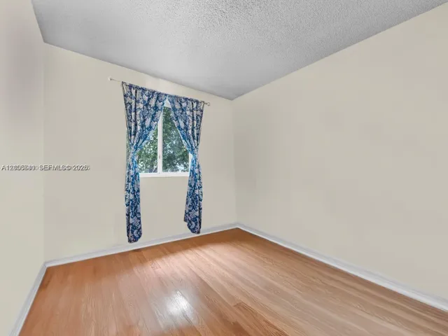 Neutral-toned interior space featuring wood-finish flooring and a single-pane window