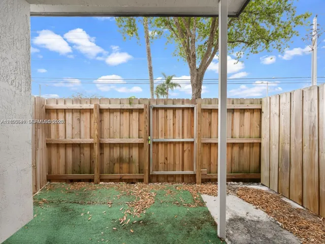 Private outdoor patio featuring a wood-panel fence, gated entry, and a covered section