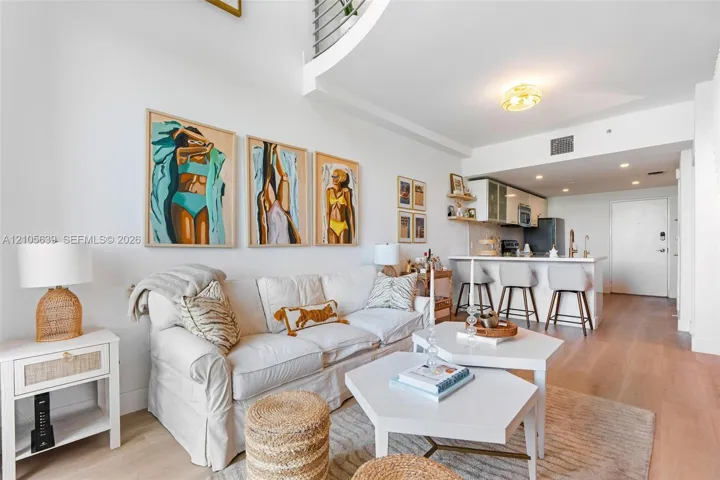 Double-height ceiling, wood-finish flooring, kitchen island with breakfast bar seating, and minimalist cabinetry