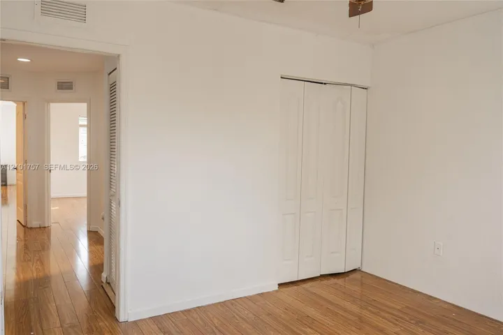 Wood-finish flooring throughout, bright white walls, and bifold closet doors
