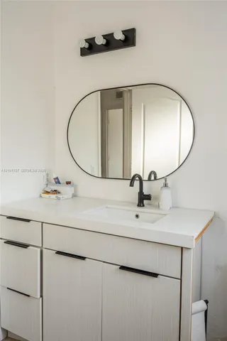 Vanity with white finish cabinetry, integrated sink, and matte black faucet