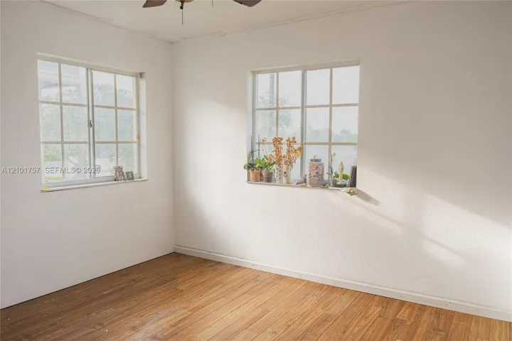 Wood-finish flooring with white walls and natural light from multiple windows