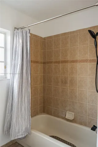 Tiled shower surround with decorative accent band and white tub