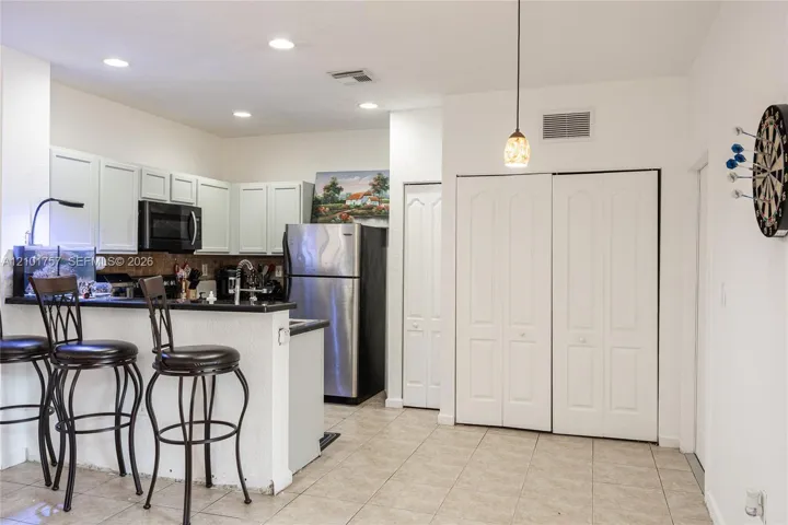 Kitchen with light-colored cabinetry and dark countertops