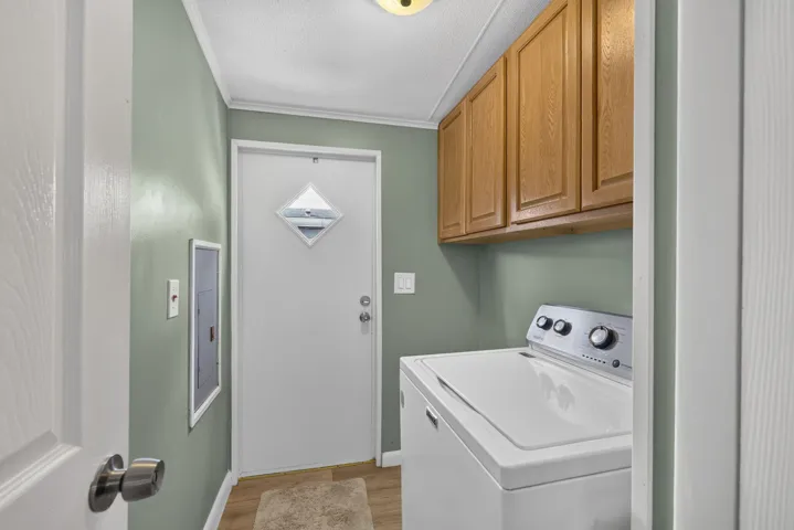 Utility room with overhead wood cabinetry, a white exterior door with diamond-shaped window, and wood-finish flooring