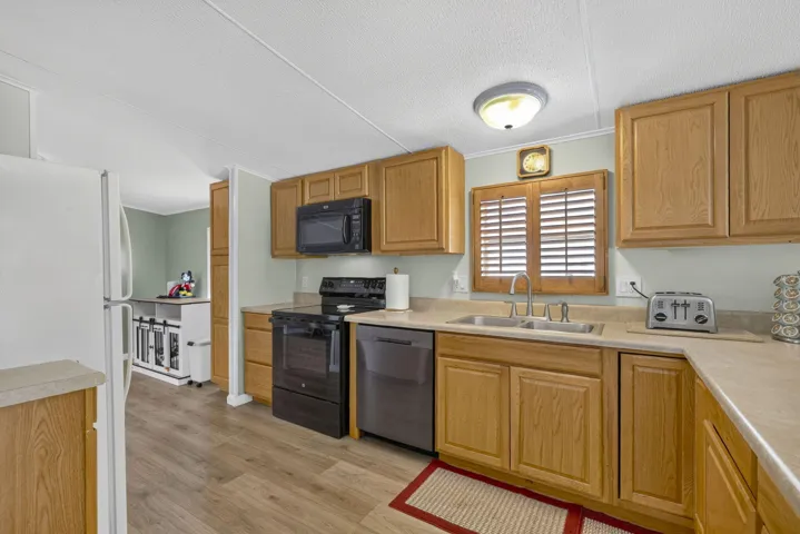 Kitchen featuring wood-finish cabinetry, laminate countertops, wood-finish flooring, and a stainless steel sink with a high-arc faucet