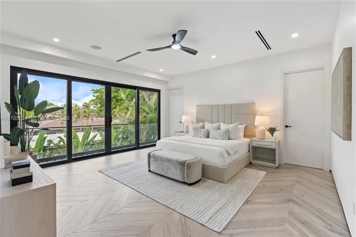 Interior space featuring chevron-patterned wood-finish flooring, floor-to-ceiling multi-panel sliding glass doors, recessed lighting, and a modern black ceiling fan