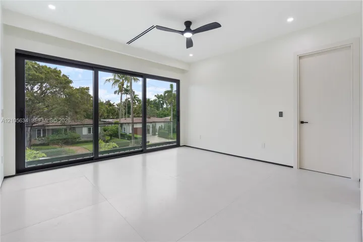 Floor-to-ceiling sliding glass doors with black frames, large-format tile flooring, recessed lighting, matte black ceiling fan, and solid-core interior door
