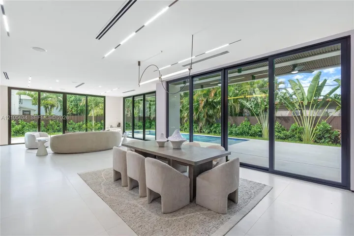 Open-concept interior featuring large-format tile flooring, recessed linear lighting, and floor-to-ceiling sliding glass doors