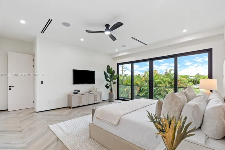 Herringbone-patterned wood-finish flooring, floor-to-ceiling glass sliding doors, recessed lighting, ceiling fan with integrated light, and built-in ceiling speakers