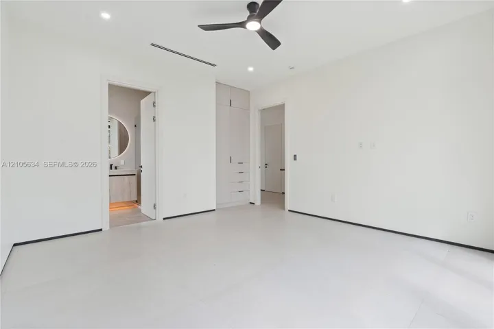 Neutral interior featuring large-format tile flooring, built-in floor-to-ceiling cabinetry, recessed lighting, and a modern three-blade ceiling fan