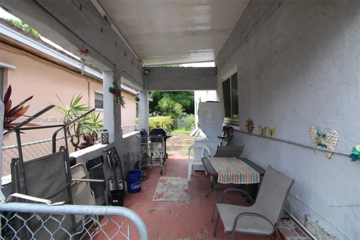 Covered exterior patio featuring a concrete floor, stucco walls, and support columns