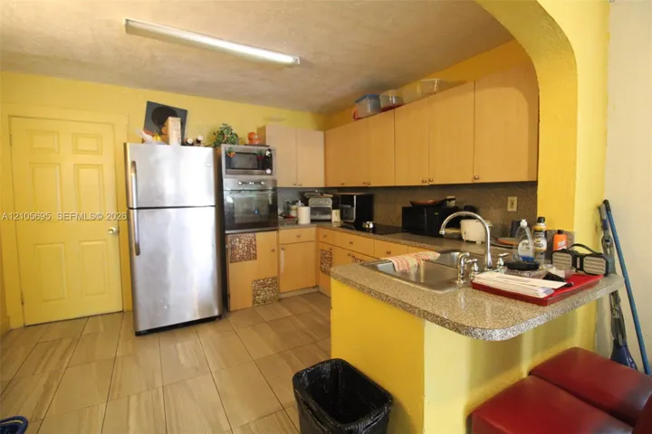 Kitchen featuring light-finish cabinetry, stone-texture countertops, ceramic tile flooring, built-in wall oven, and a double-basin stainless steel sink