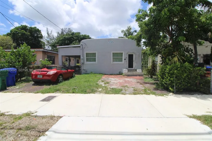 Single-story exterior featuring a smooth-stucco facade, attached carport, and decorative gable vent detail